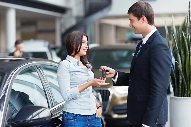 an exchange of a car key between two people, taking place in a car dealership
